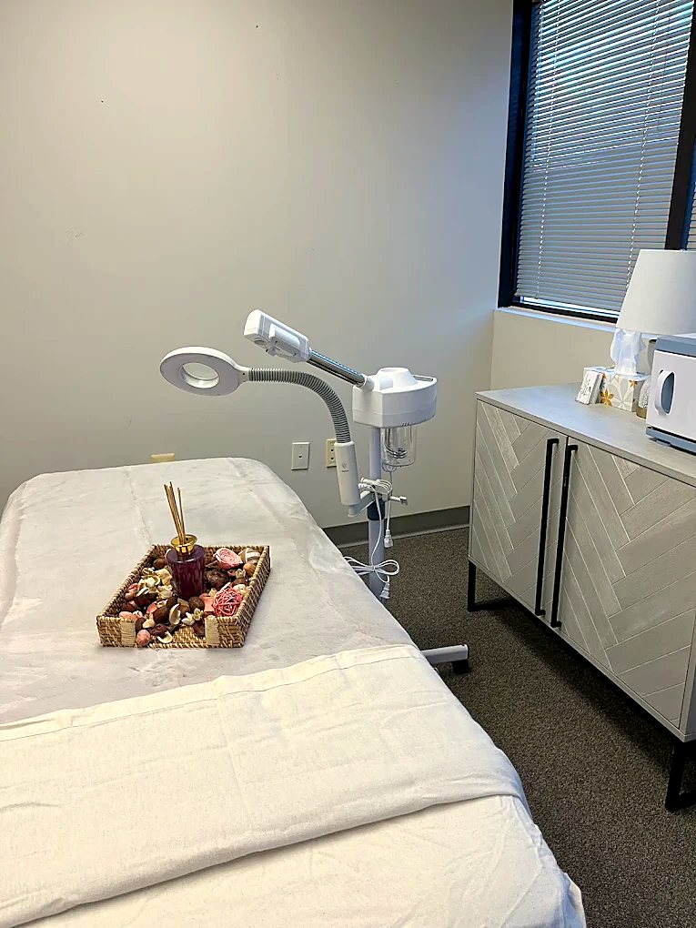 Bright treatment room with facial steamer and massage table